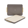 Two latte-colored Reserve Bakeware 13″ x 18″ half sheet pans made of aluminized steel with gold-tone handles, 2-piece set.