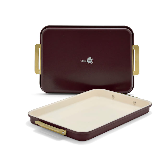 Two burgundy nonstick aluminized steel quarter sheet pans with cream interiors and gold-toned handles.