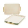 Set of two sage green quarter sheet pans with cream interiors and gold handles.
