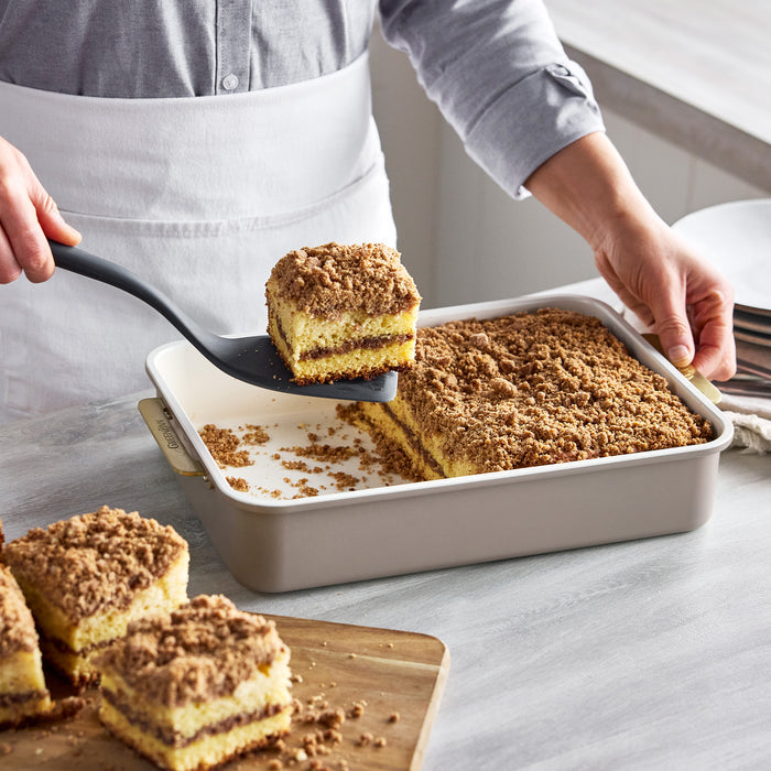 A spatula lifting a crumb cake square from a Reserve Bakeware 8-piece latte aluminized steel pan.