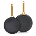 Two black frying pans with gold handles on a white background