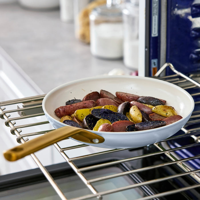 Light blue frying pan with sausages and potatoes in an oven