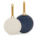 Two dark blue frying pans with gold handles on a white background