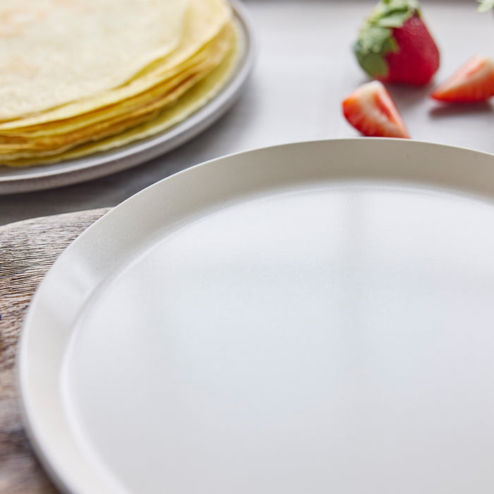 Close-up of a crepe pan with crepes and berries in the background