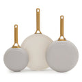 Three taupe gray frying pans with gold handles on a white background