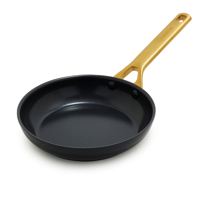 Black frying pan with a gold handle on a white background
