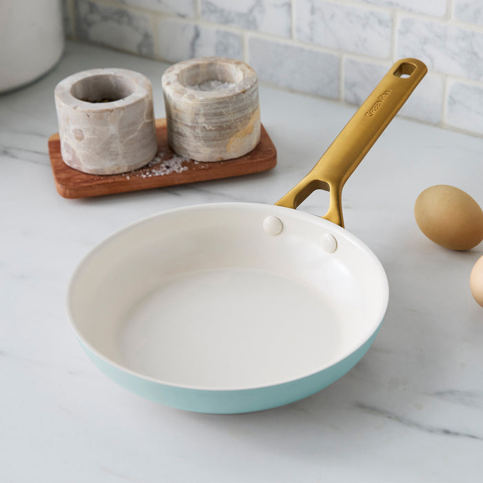 Light blue frying pan with gold handle on a kitchen counter