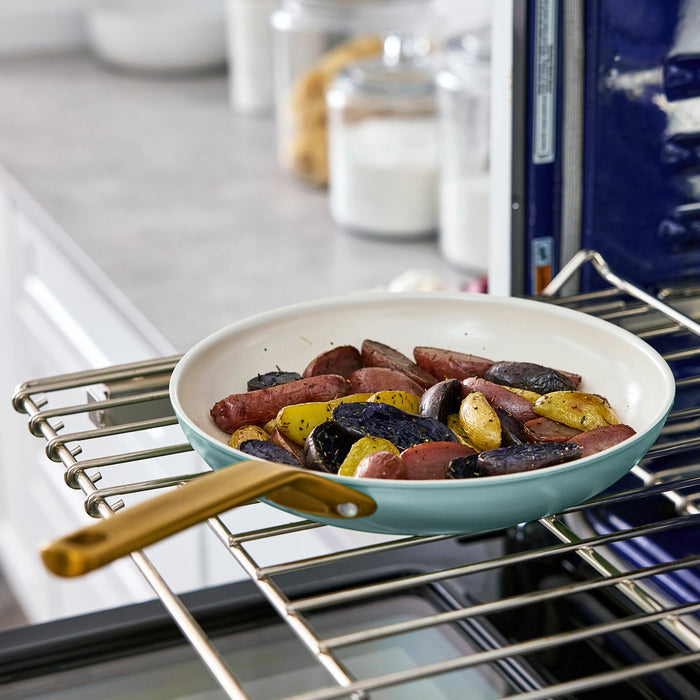 Light blue frying pan with sausages and potatoes in an oven