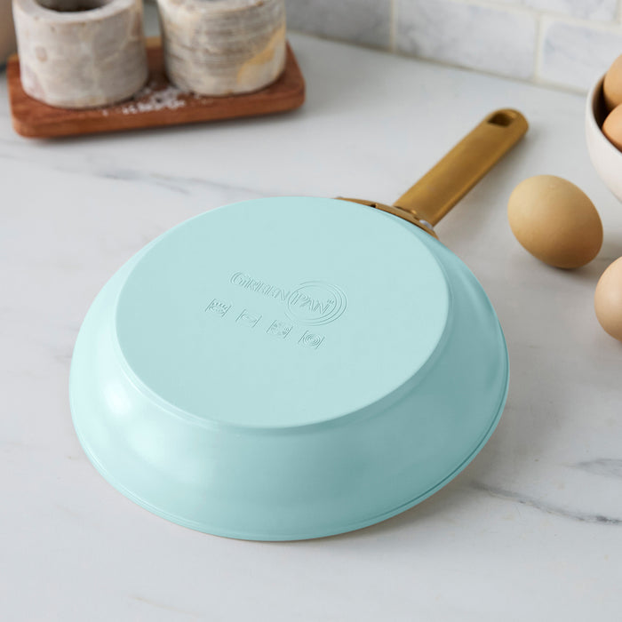 Light blue frying pan with a gold handle on a kitchen counter.