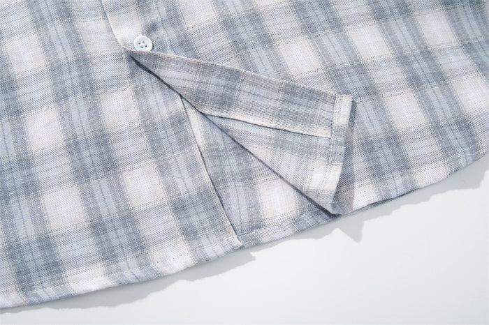 Close-up of the shirttail hem and side seam on light gray plaid fabric