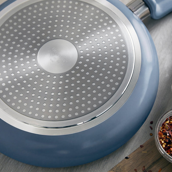 Dutch Blue ceramic nonstick pan with dotted metal base beside spices on a gray countertop.