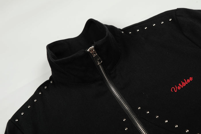 Close-up of black jacket collar and zipper with shoulder studs and red logo embroidery