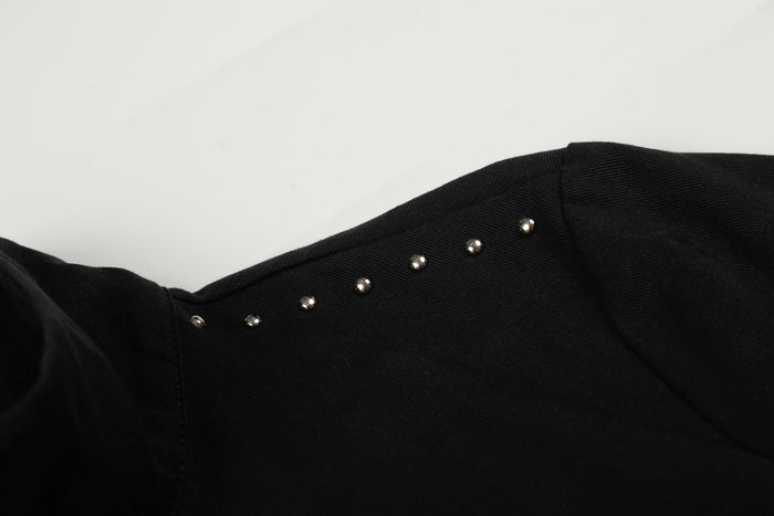 Close-up of studded shoulder seam on black cropped jacket