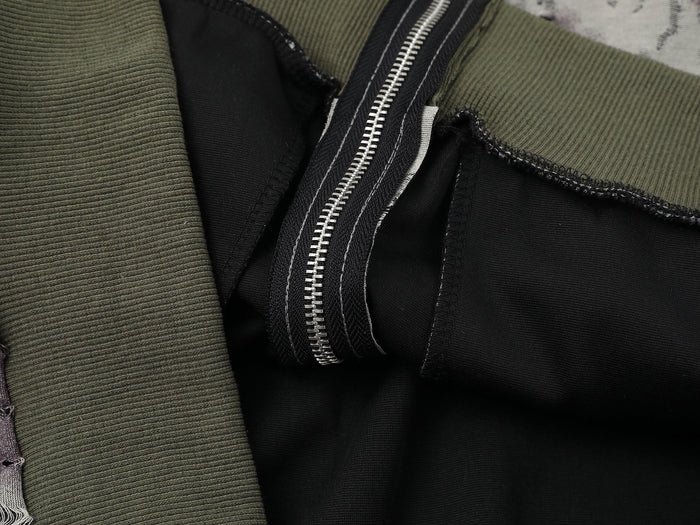 Close-up of olive ribbed hem and black zipper placket