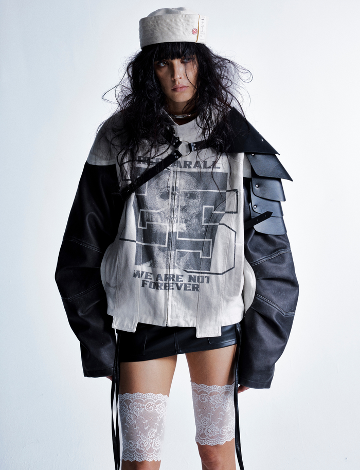 Model wearing cream and black skull graphic moto jacket with layered shoulder detail