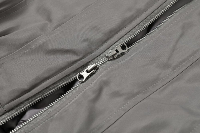 Close-up of gray bomber jacket front zipper and metal pull tabs