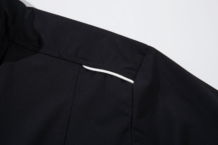 Close-up of black shoulder panel with white piping on the track jacket