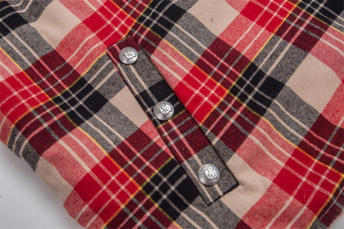 Close-up of red plaid jacket sleeve with snap buttons and pocket tabs