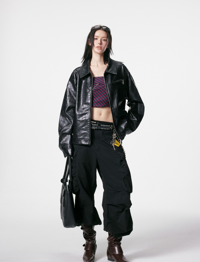 Full-length model view of black PU leather jacket with cargo pants and belt chain
