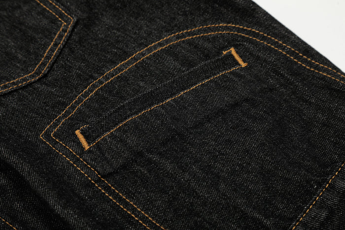 Close-up of a black denim jacket chest pocket with tan contrast stitching
