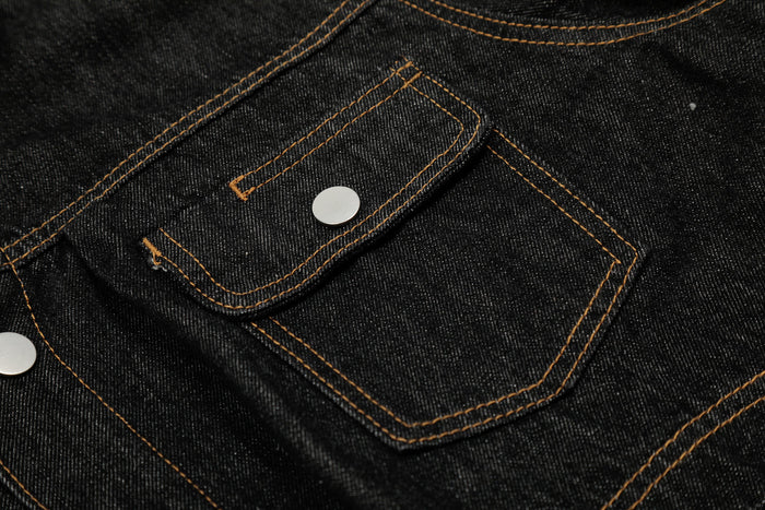 Close-up of a black denim jacket flap pocket and snap button