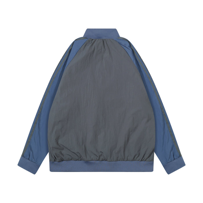Back view of blue and charcoal nylon track jacket with blue trim and ribbed cuffs