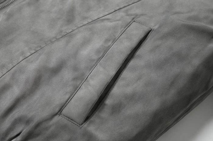 Close-up of grey bomber jacket sleeve pocket with angled welt opening