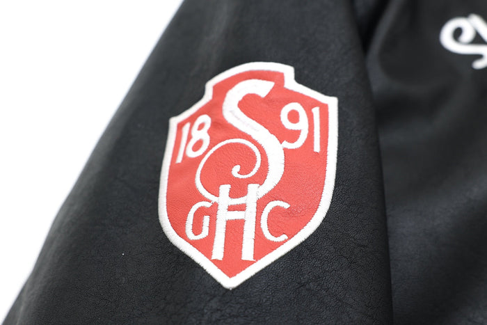 Close-up of red shield patch on black faux leather sleeve
