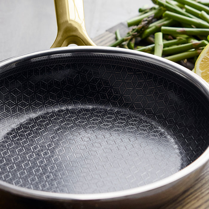 Gold hybrid ceramic 8-inch frypan with a geometric pattern, next to chopped asparagus and a lemon slice.