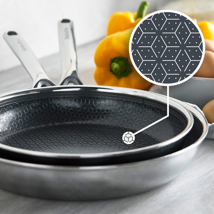 Set of three ceramic nonstick frypans in different sizes next to yellow bell peppers and brown eggs.