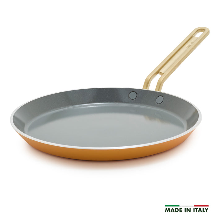 Yellow crepe pan with a gold handle on a white background