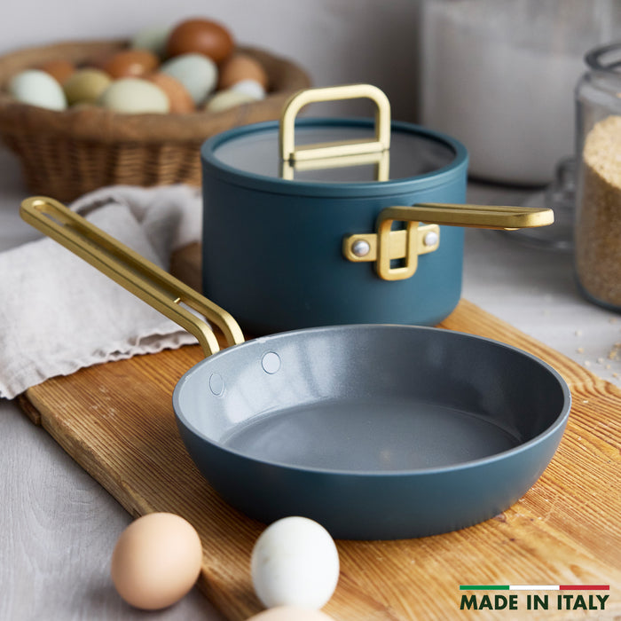Ceramic nonstick 3-piece mini cookware set in Venetian teal with gold handles; eggs in background.