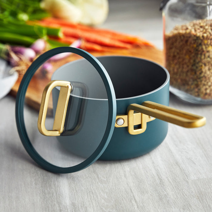 Venetian Teal ceramic nonstick 3-piece mini cookware set on a counter with assorted vegetables in the background.