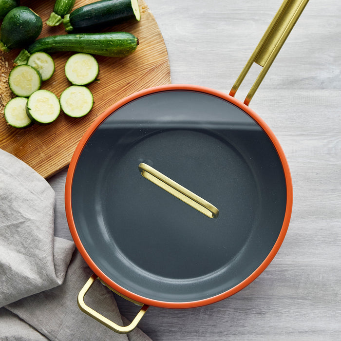 Ceramic nonstick 4.5-quart pan in Amalfi Sunset color next to sliced zucchini on a wooden board and gray cloth.