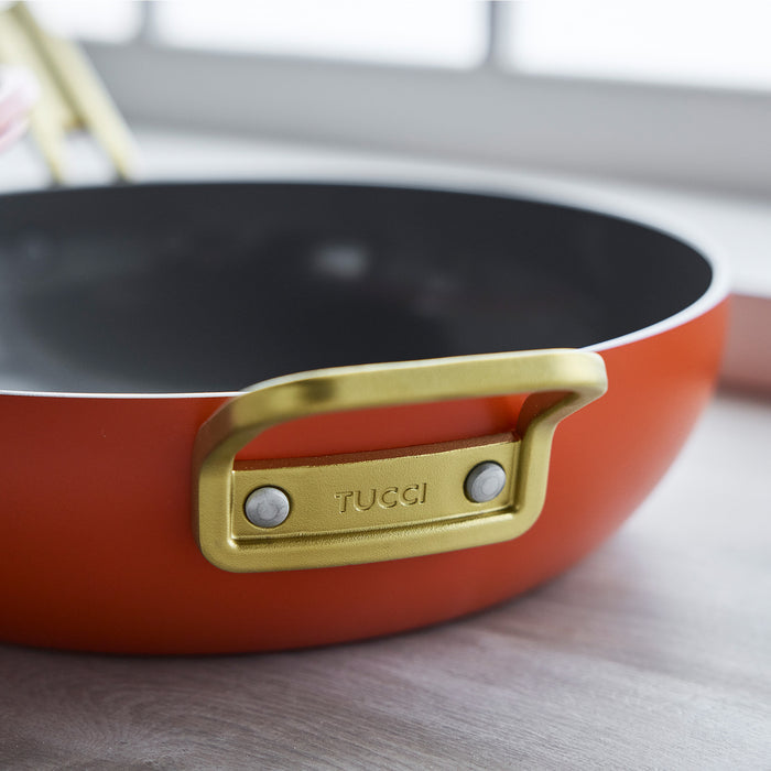 Ceramic nonstick pan in Amalfi Sunset orange with gold handle, 4.5-quart size, on a countertop.
