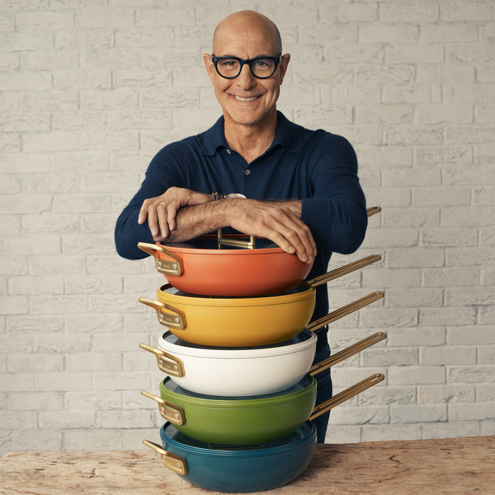 Man with glasses smiling, leaning on a stack of orange ceramic nonstick pans.