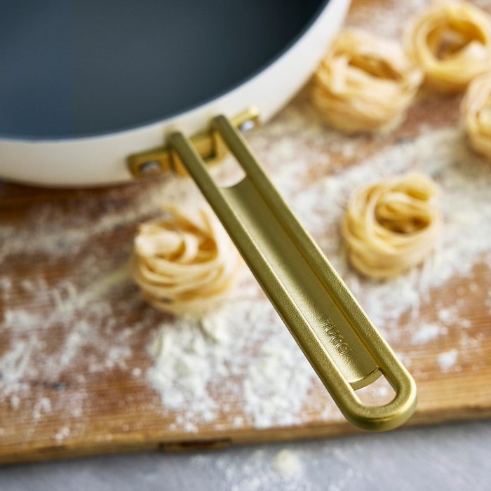 White ceramic nonstick 4.5-quart pan with handles, Stanley Tucci line, shown on a kitchen surface.