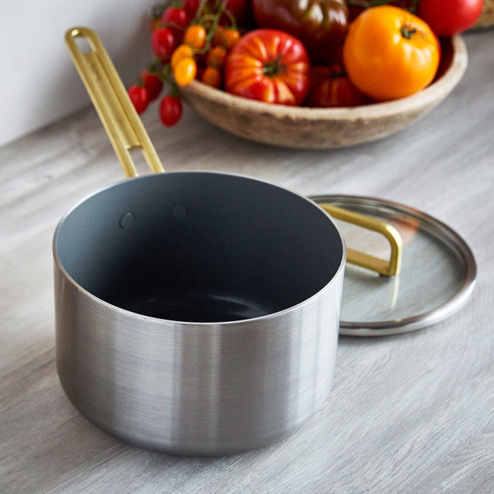 Stainless steel 4-quart saucepan with champagne-colored handles next to fresh tomatoes.