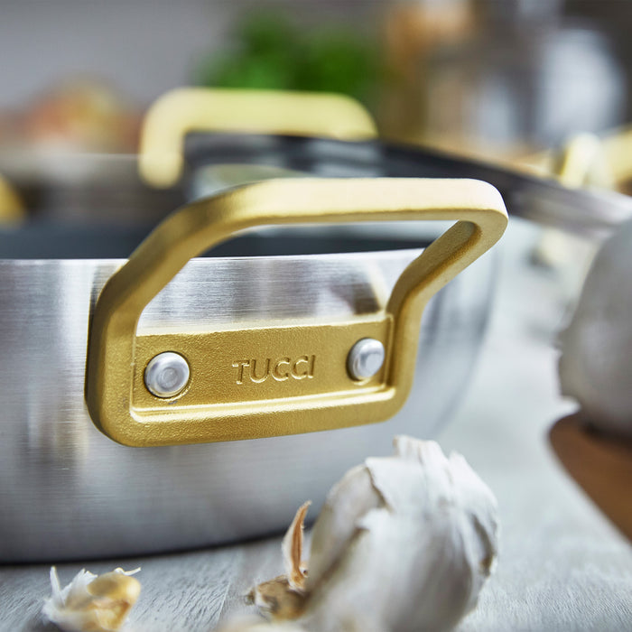 Stainless steel ceramic 4.5-quart pan with lid, gold handle, and garlic cloves on the side.