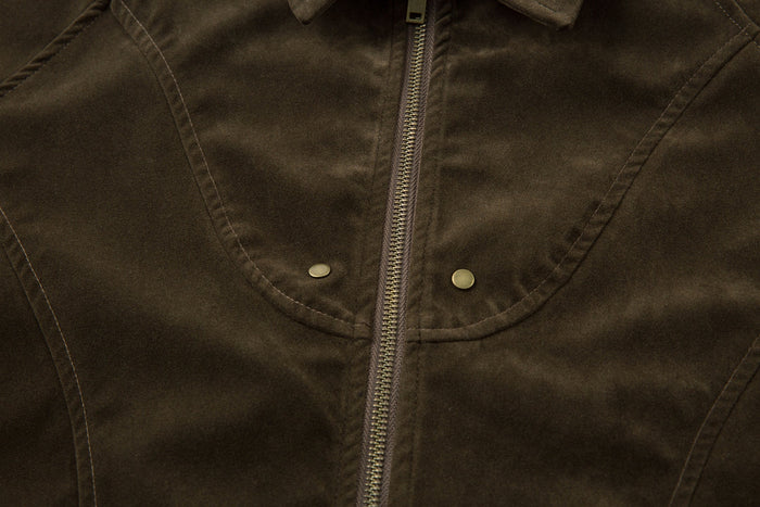 Close-up of the olive jacket chest with curved seam details and brass zipper