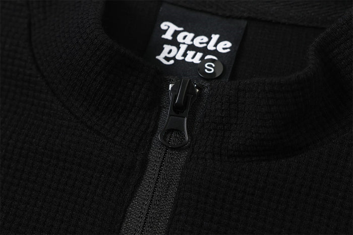 Close-up of black half-zip collar and neck label on textured sweatshirt