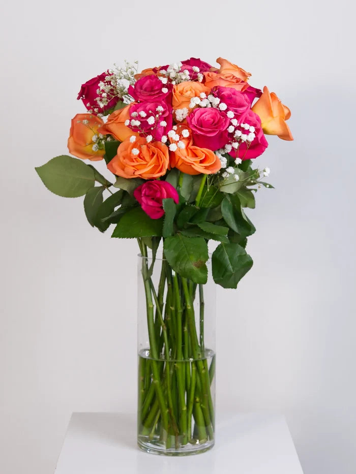 Hot pink and orange rose bouquet with gypsophila in glass vase