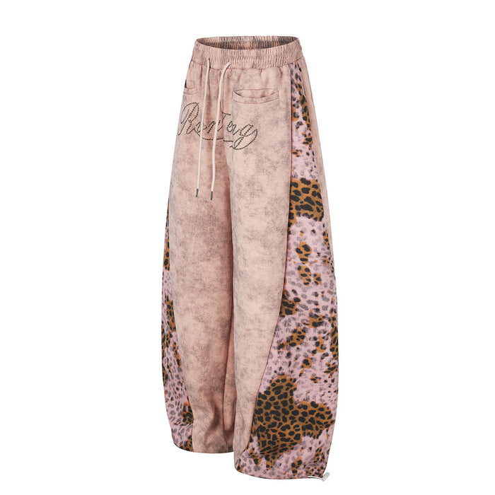 Angled front view of pink wide-leg sweatpants with leopard print patchwork side panels and drawstring waist
