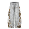 Front view of gray wide-leg sweatpants with leopard print patchwork side panels and rhinestone script