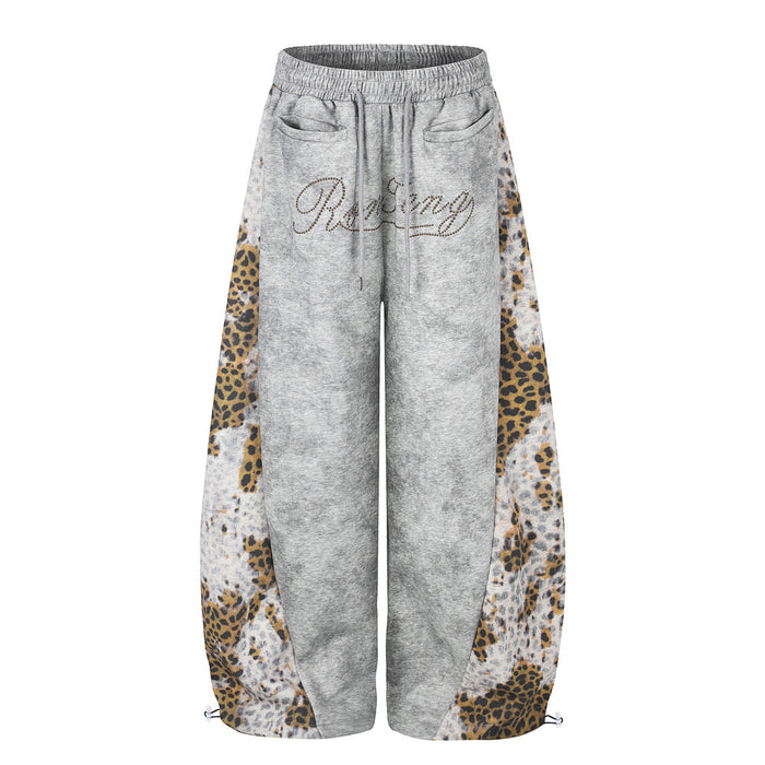 Front view of gray wide-leg sweatpants with leopard print patchwork side panels and rhinestone script