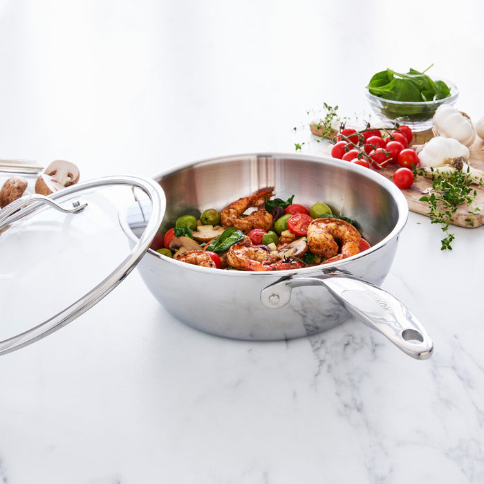 Stainless steel chef's pan with food on a marble surface