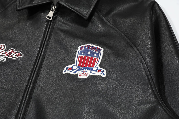 Close-up of black bomber jacket chest patch and front zipper under collar