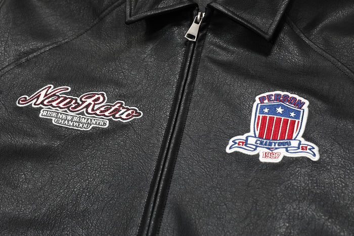 Close-up of black bomber jacket front chest with script patch and crest patch