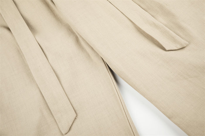 Close-up of beige belt ties draped over pleated trousers fabric