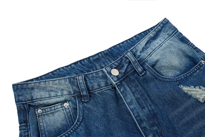 Close-up of blue denim waistband with button closure, belt loops, and faded wash